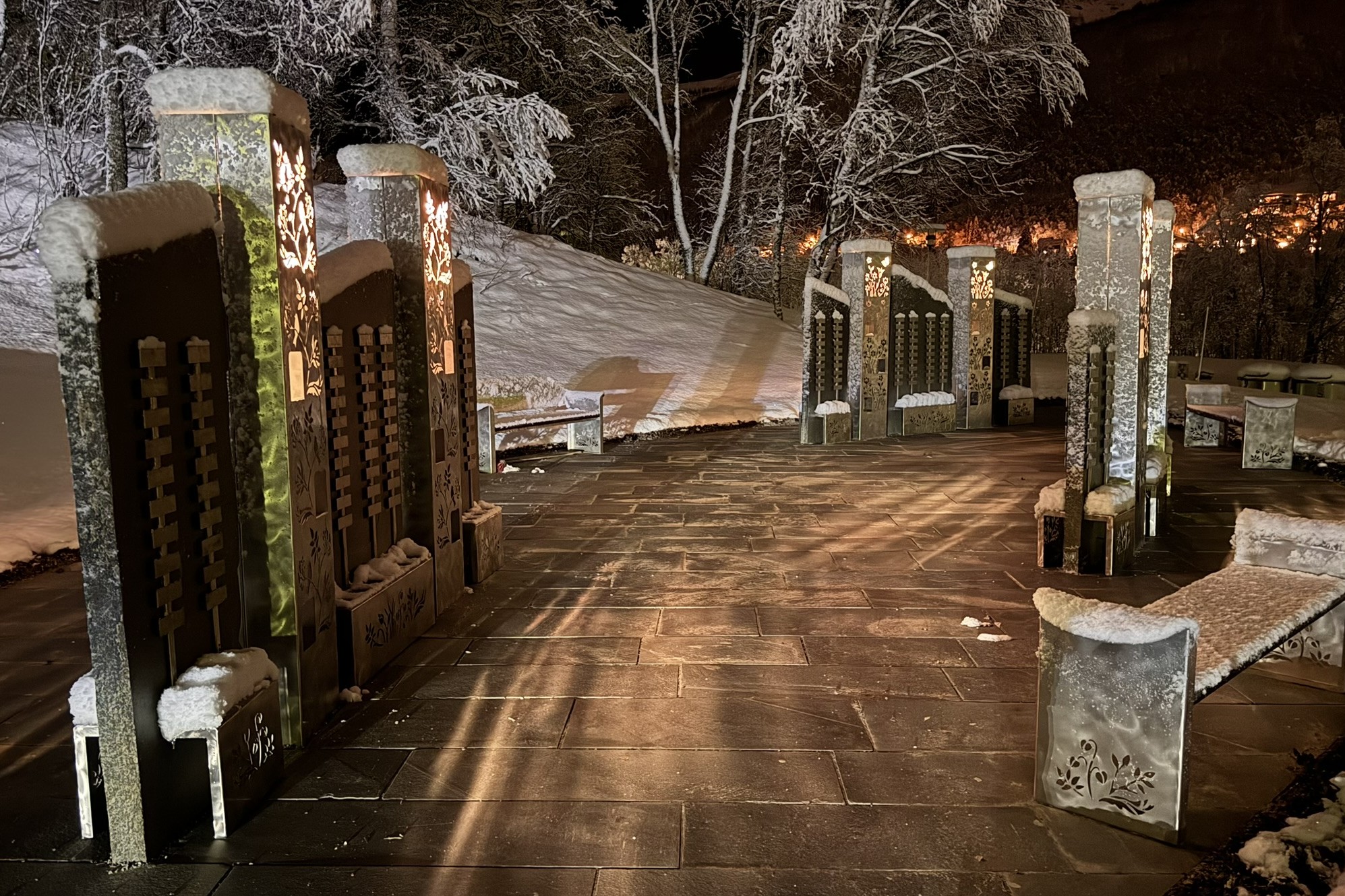 Elvestad urneminnelund på kveldstid, med opplyste minnesøyler og snødekt vinterlandskap.