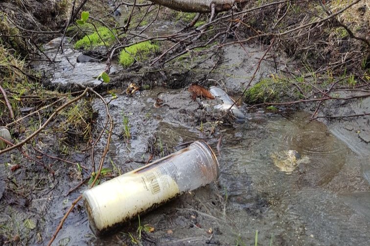 Plastbaserte gravlykter i en bekk nær gravplass.